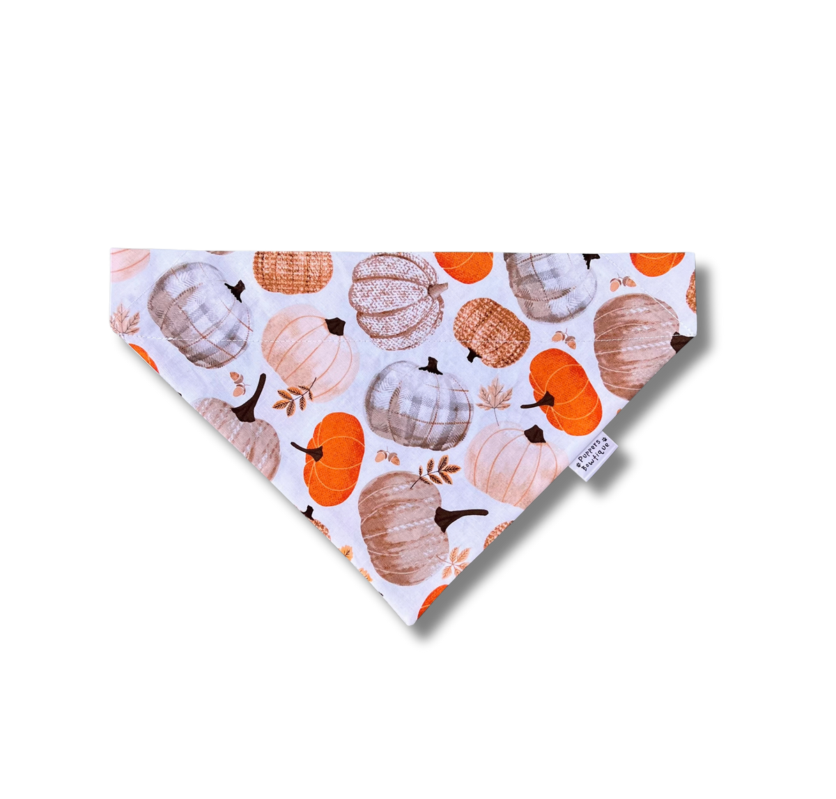 A triangular bandana-style pet collar or scarf with an all-over autumn pumpkin print, featuring orange, beige, and brown pumpkins on a white background. A small white brand tag reading 'The Pumpkin Patch Co.